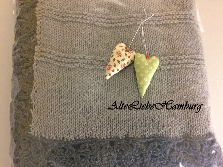 Strickdecke in hellgrau mit dunkelgrauen Blümchen