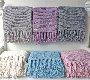 Handgestrickte Tagesdecken in blau, weiß, rose, lila und hell- und mittelgrauen Farben und Wolltönen