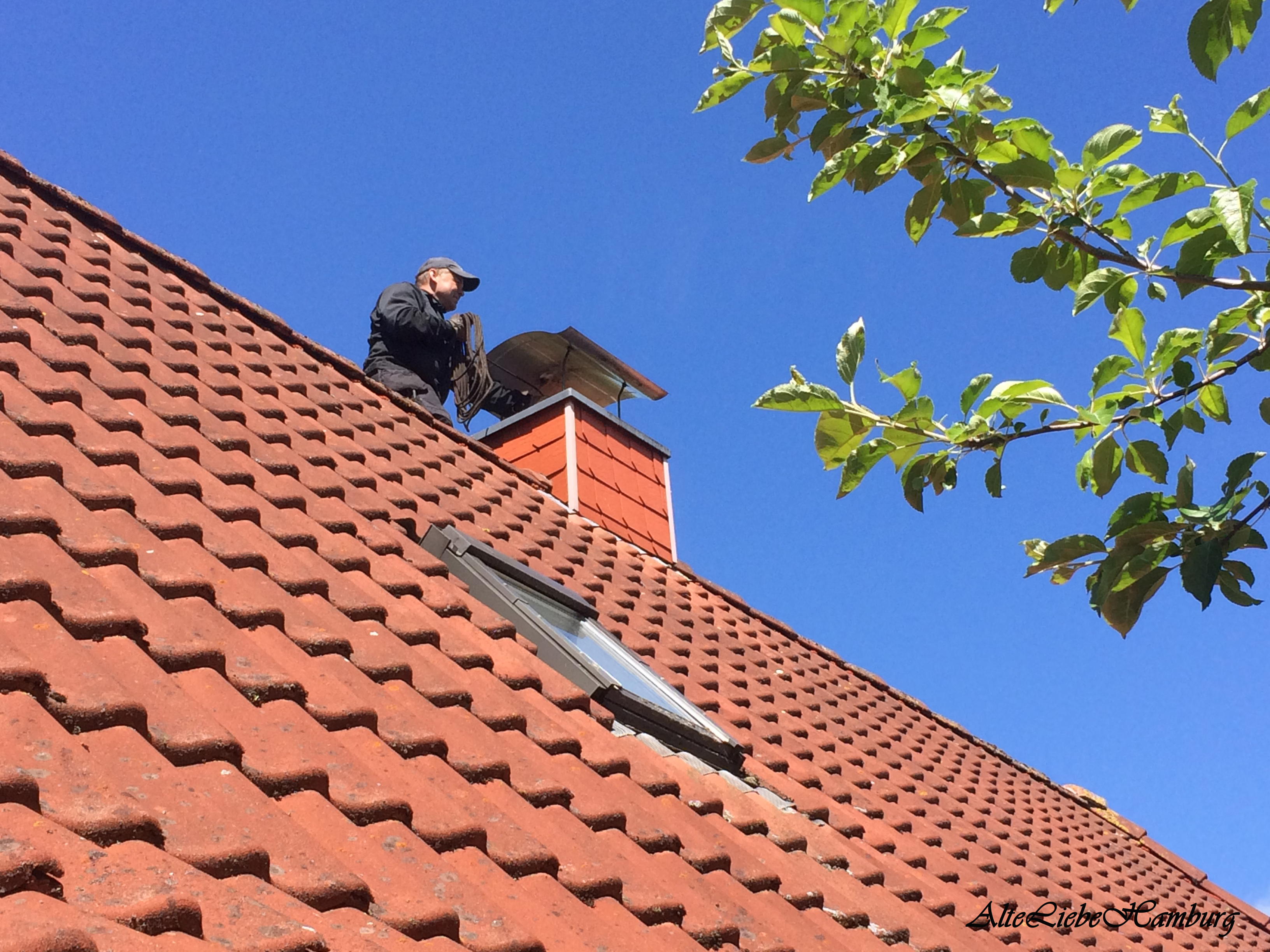 Schornsteinfeger auf dem Dach strahlend blauer Himmel