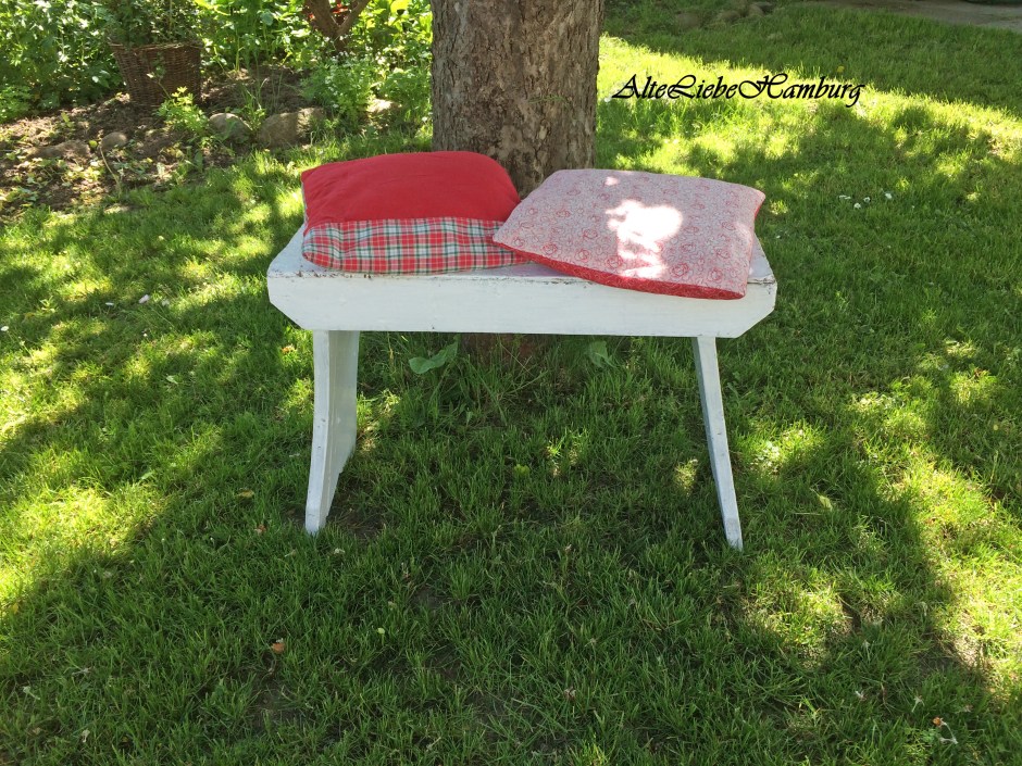 Alte Holzbank vor einem Apfelbaum im Garten