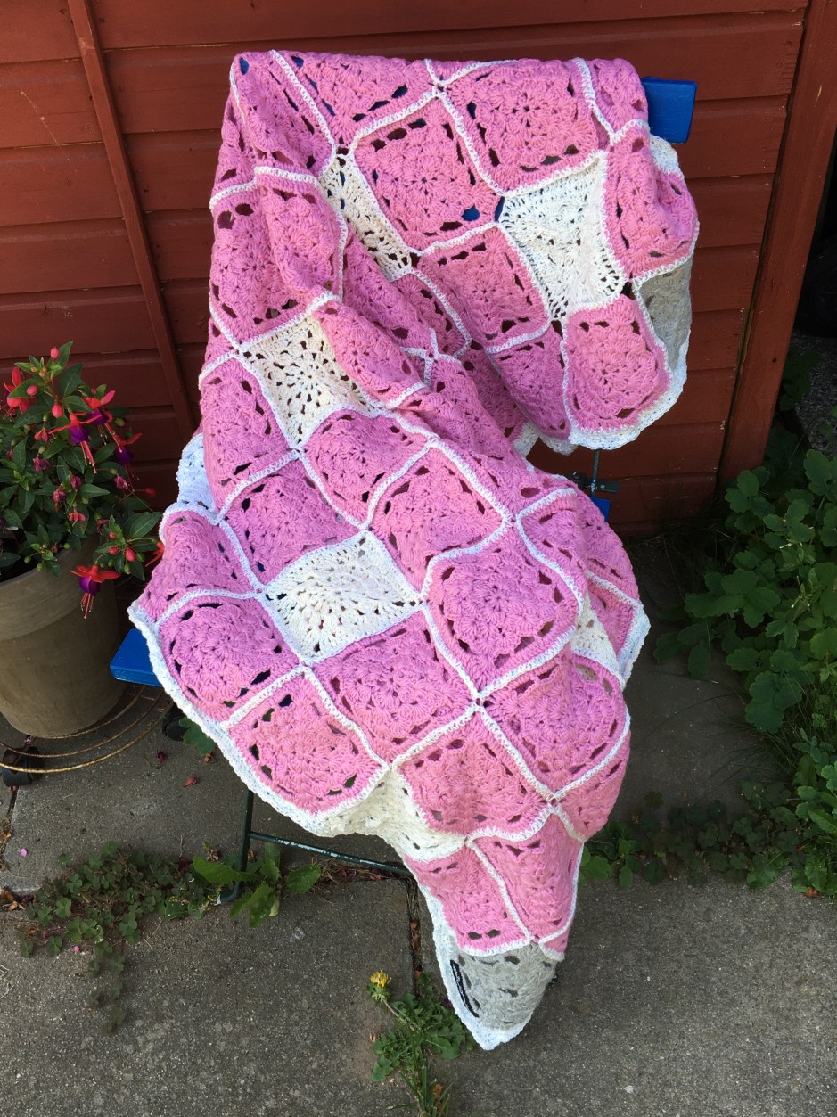 Gehäkelte Granny Square Decke über einem Stuhl liegend