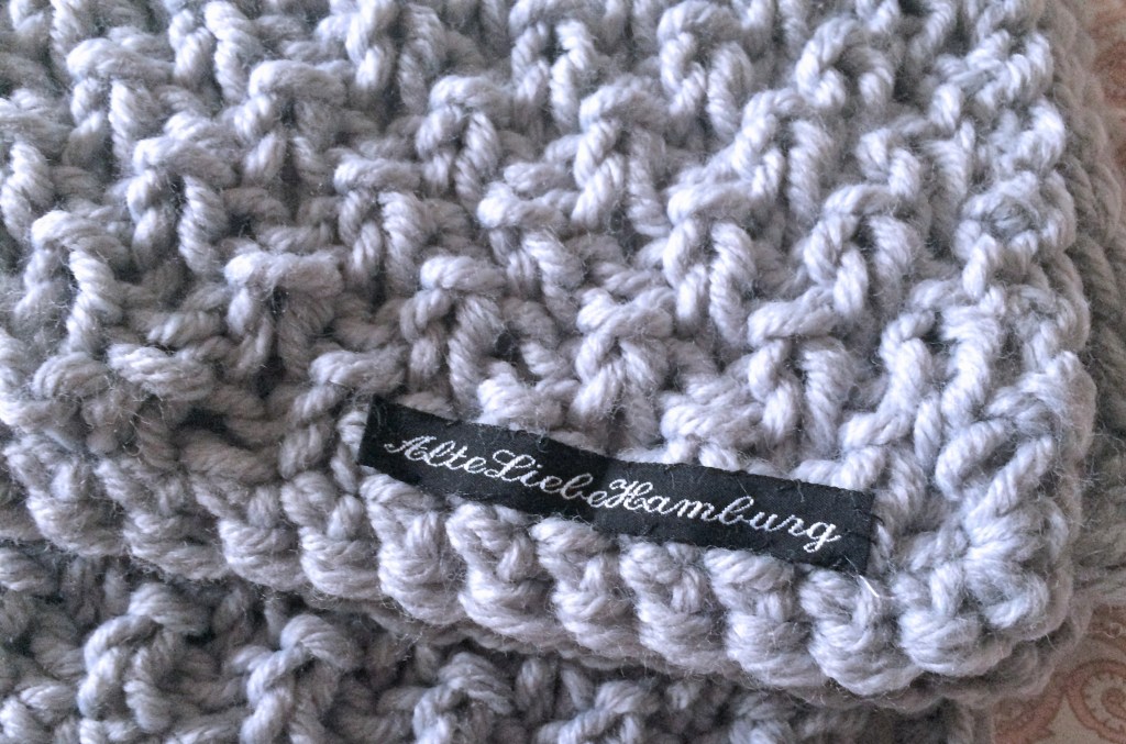 Tagesdecke aus grauer Wolle grobstrick mit Schild AlteLiebeHamburg aufgenäht