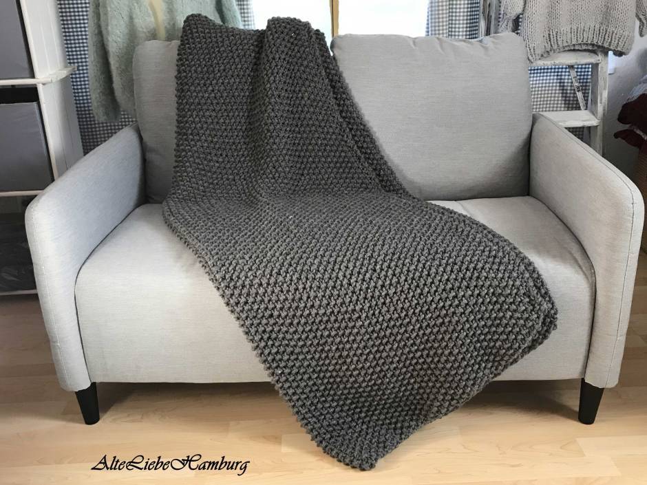 Dunkel graue Tagesdecke handgefertigt liegt auf einem grauen Zweisitzer Sofa