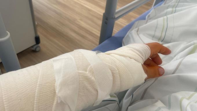 Ein Arm im Gips liegt auf einem Bett.