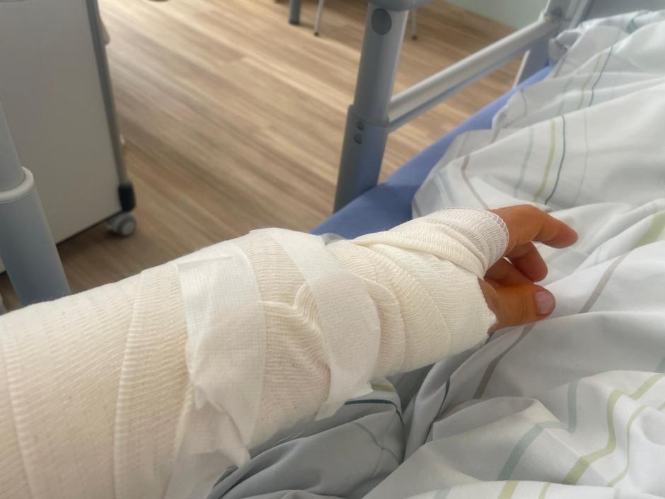 Ein Arm im Gips liegt auf einem Bett.