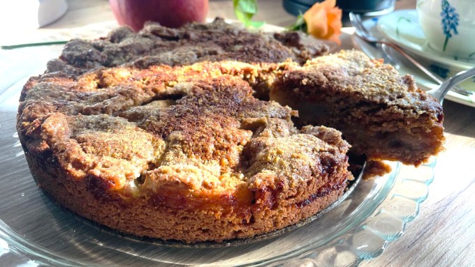 Fertig gebackener gedeckter Apfelkuchen, angeschnitten, mit Apfel und Rose dekoriert